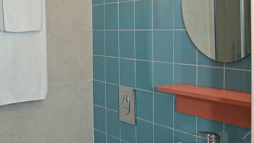 A bathroom with a white sink, a mirror, and a towel hanging on a rack.