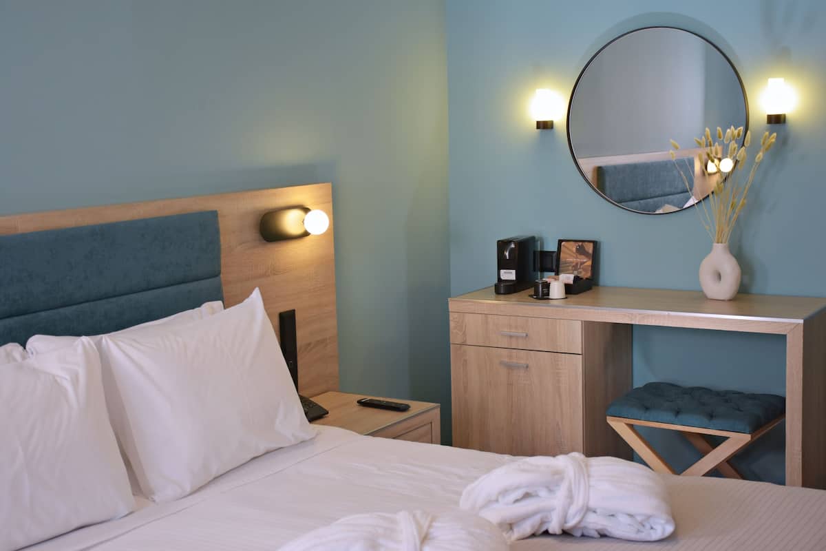 Une chambre d’hôtel équipée d’un lit, d’une table de chevet, d’un bureau et d’un miroir.