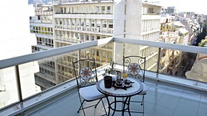 Un balcó amb taula i cadires, amb vista a un paisatge urbà ple d'edificis.