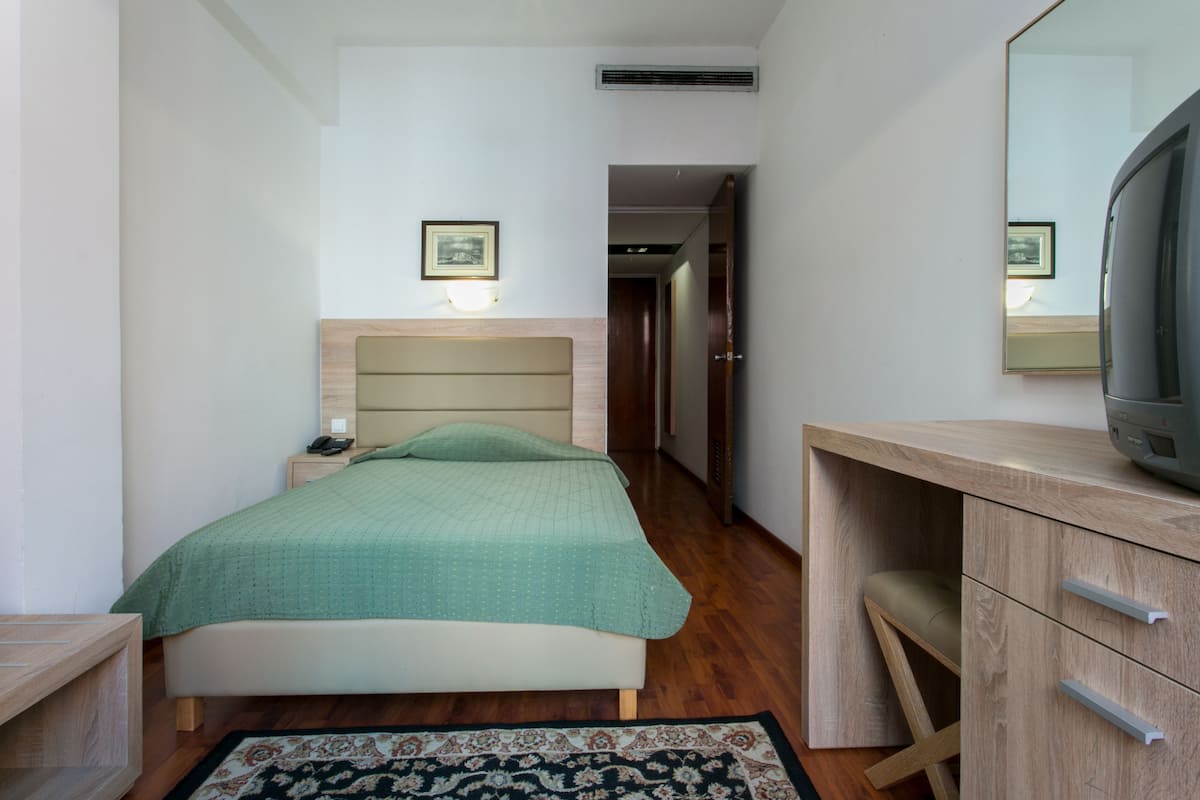 Une chambre à coucher avec un lit, une table de chevet, une lampe et un miroir.