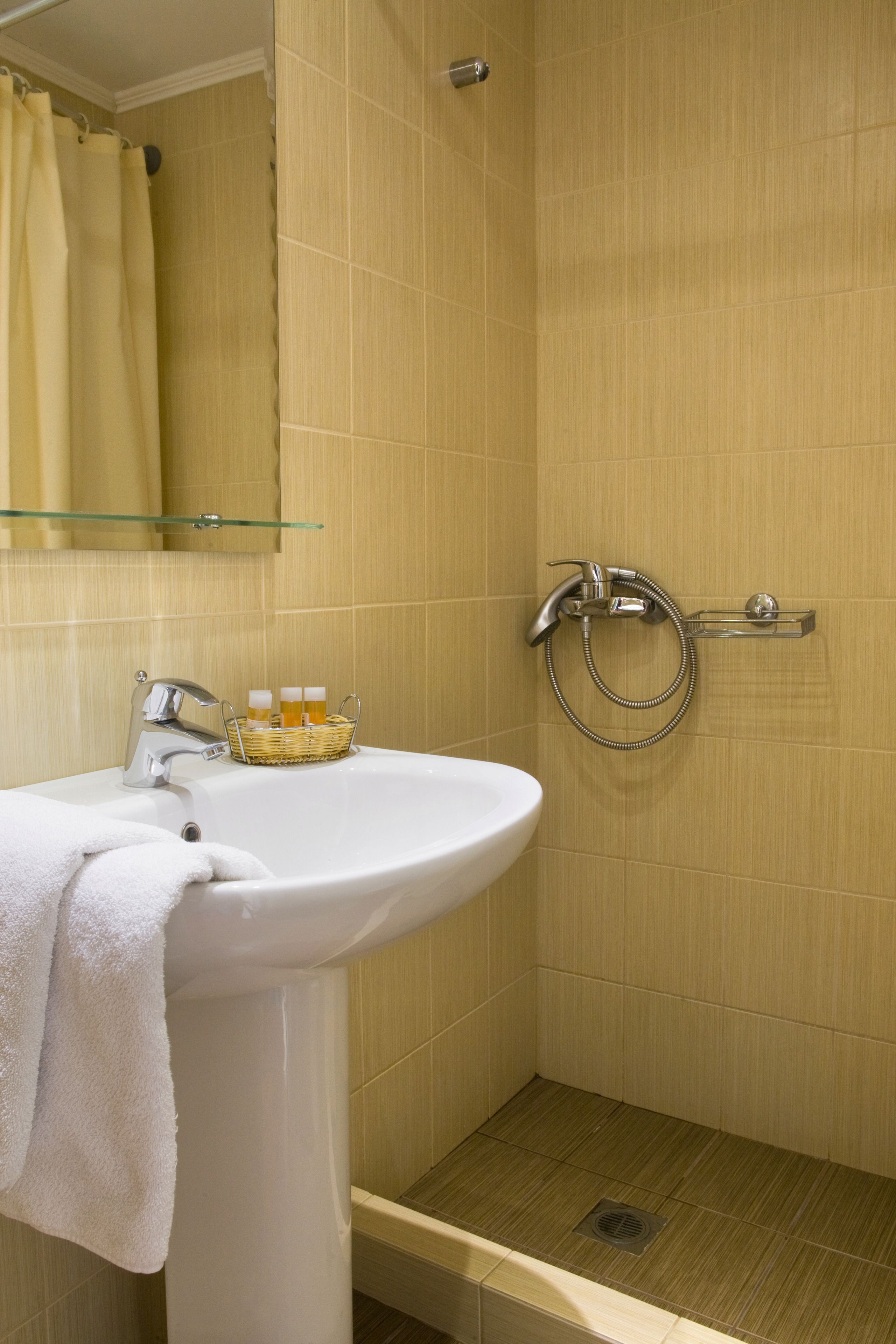 A bathroom with a white sink, a glass shelf above it, and a shower area with a glass door.