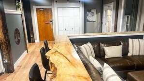 A modern living room with a wooden dining table, leather sofa, and a large window. - Old Mill Inn (Hatfield)