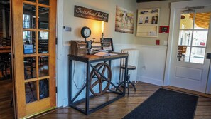 A rustic interior with a wooden table, a vintage clock, and a push button for assistance. - Old Mill Inn (Hatfield)