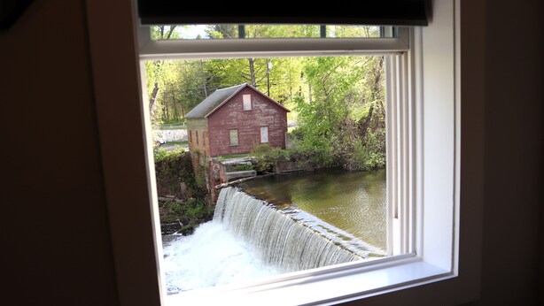 A view of a red building by a waterway through a window. - Old Mill Inn (Hatfield)