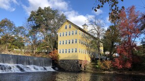 A yellow multi-story building with a water feature in front. - Old Mill Inn (Hatfield)
