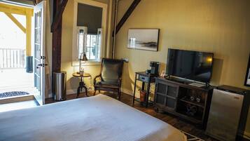 A hotel room with a bed, a television, a chair, a small table, and a window.