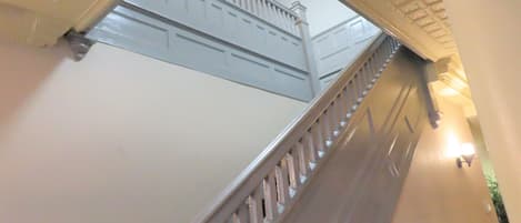 Una escalera con barandillas blancas y un techo con diseño de cuadrícula.