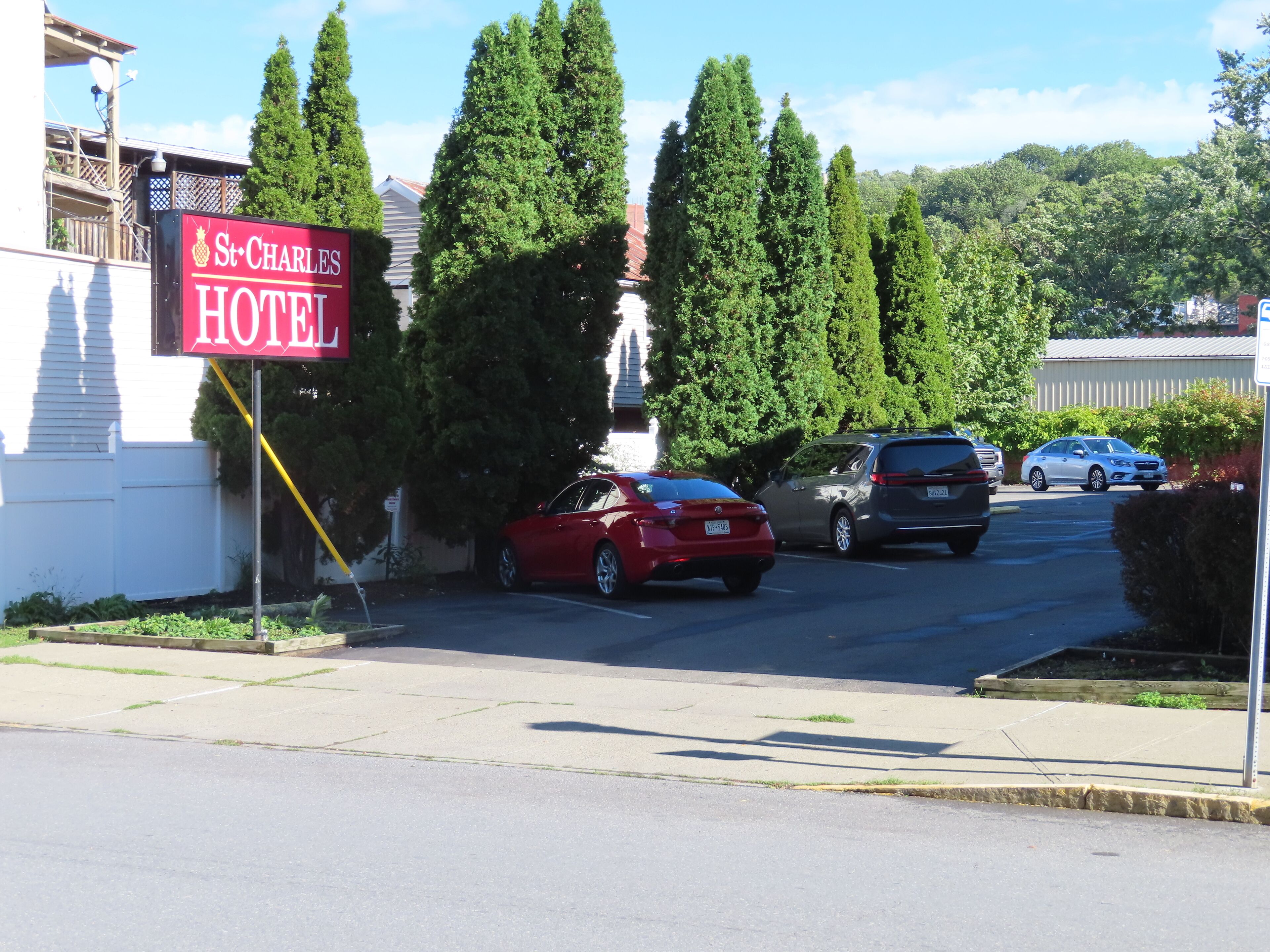 A hotel sign, parked cars, and a clear sky.