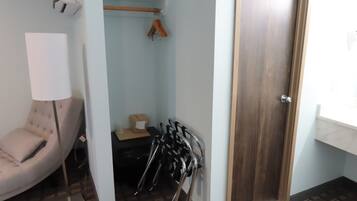 Ein kleines Zimmer mit Stuhl, Tisch, Kleiderhaken und einer Tür.