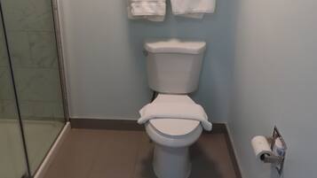 A bathroom with a toilet, a towel rack with towels, and a toilet paper holder.