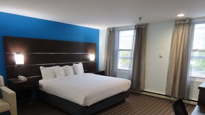 Une chambre d’hôtel avec un grand lit, une table de chevet, une chaise et un bureau.