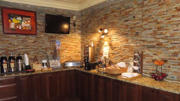 A kitchen with a brick wall, a flat-screen TV, and various appliances. - St. Charles Hotel (Hudson)
