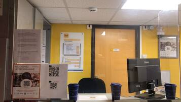 A reception desk with a computer, two blue cups, and informational posters on the wall.
