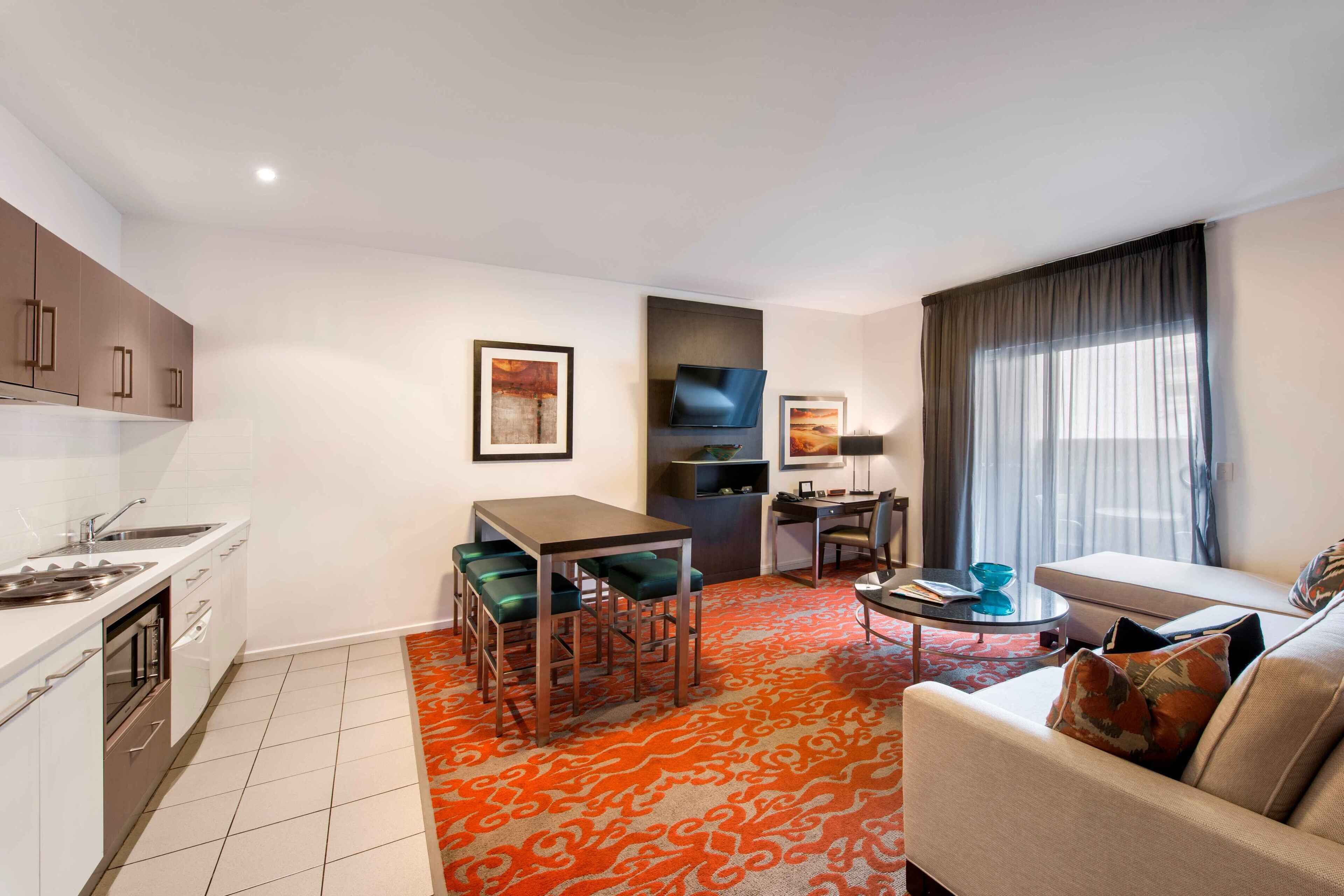 A modern hotel room with a kitchen, dining area, and living space.