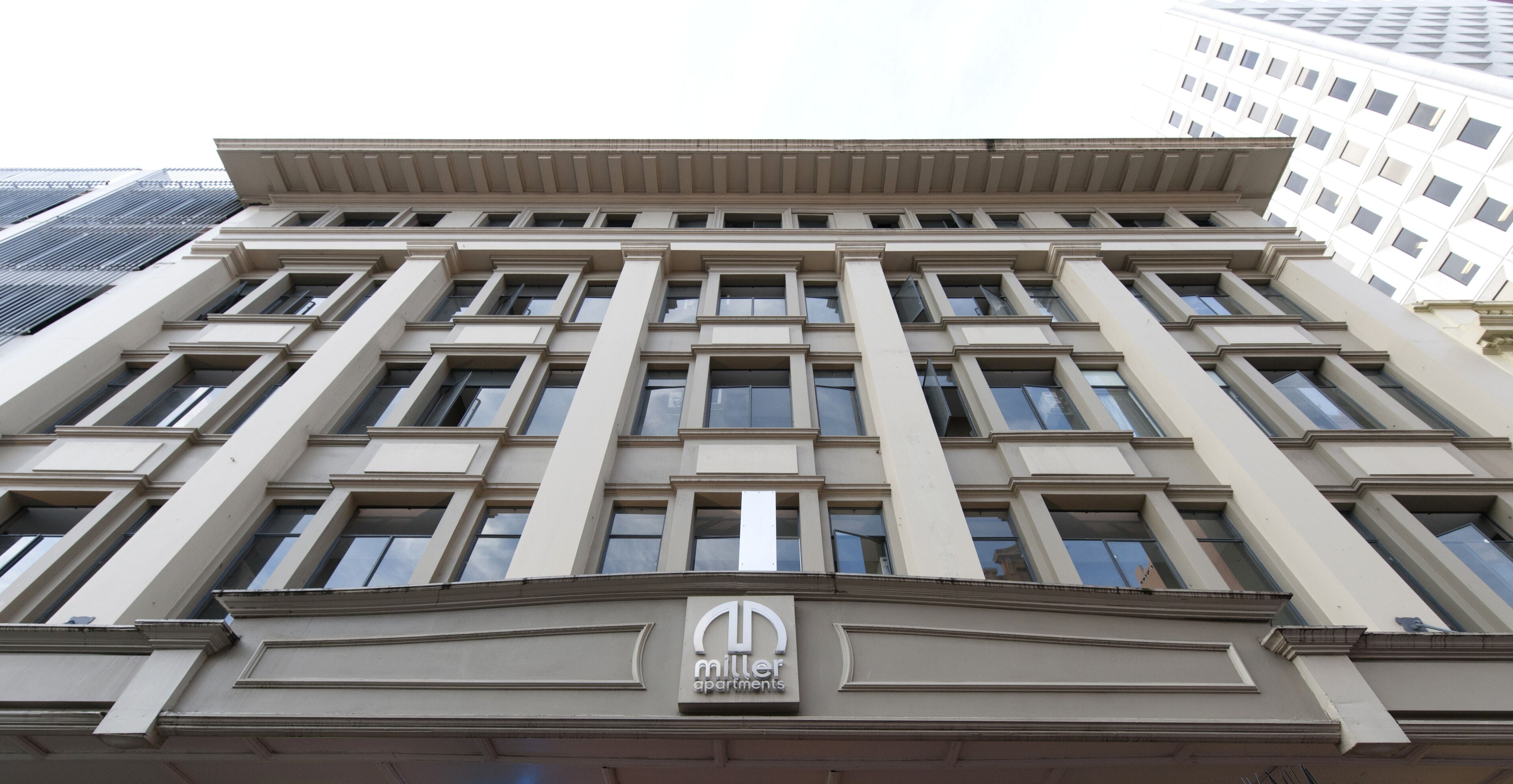 A multi-story building with a classical architectural style, featuring a prominent "Miller Apartments" sign at the ground level.