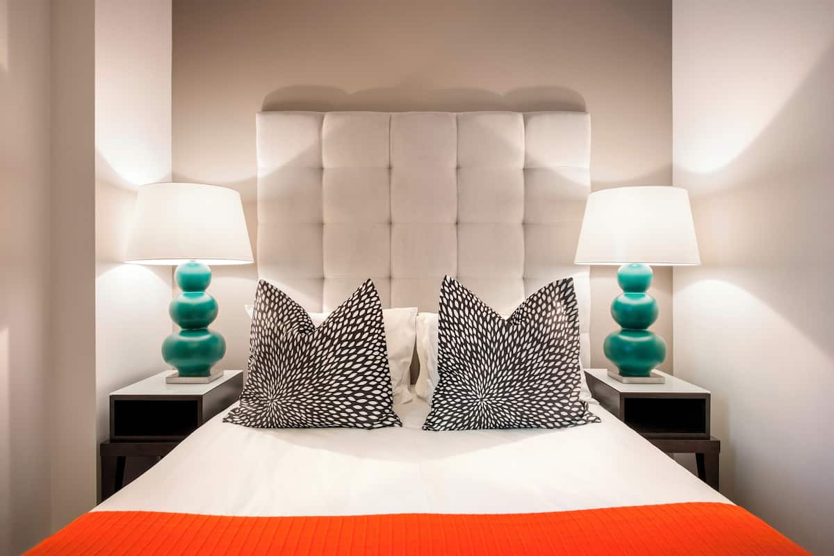 Una habitación de hotel con una cama grande, dos mesitas de noche y dos lámparas.