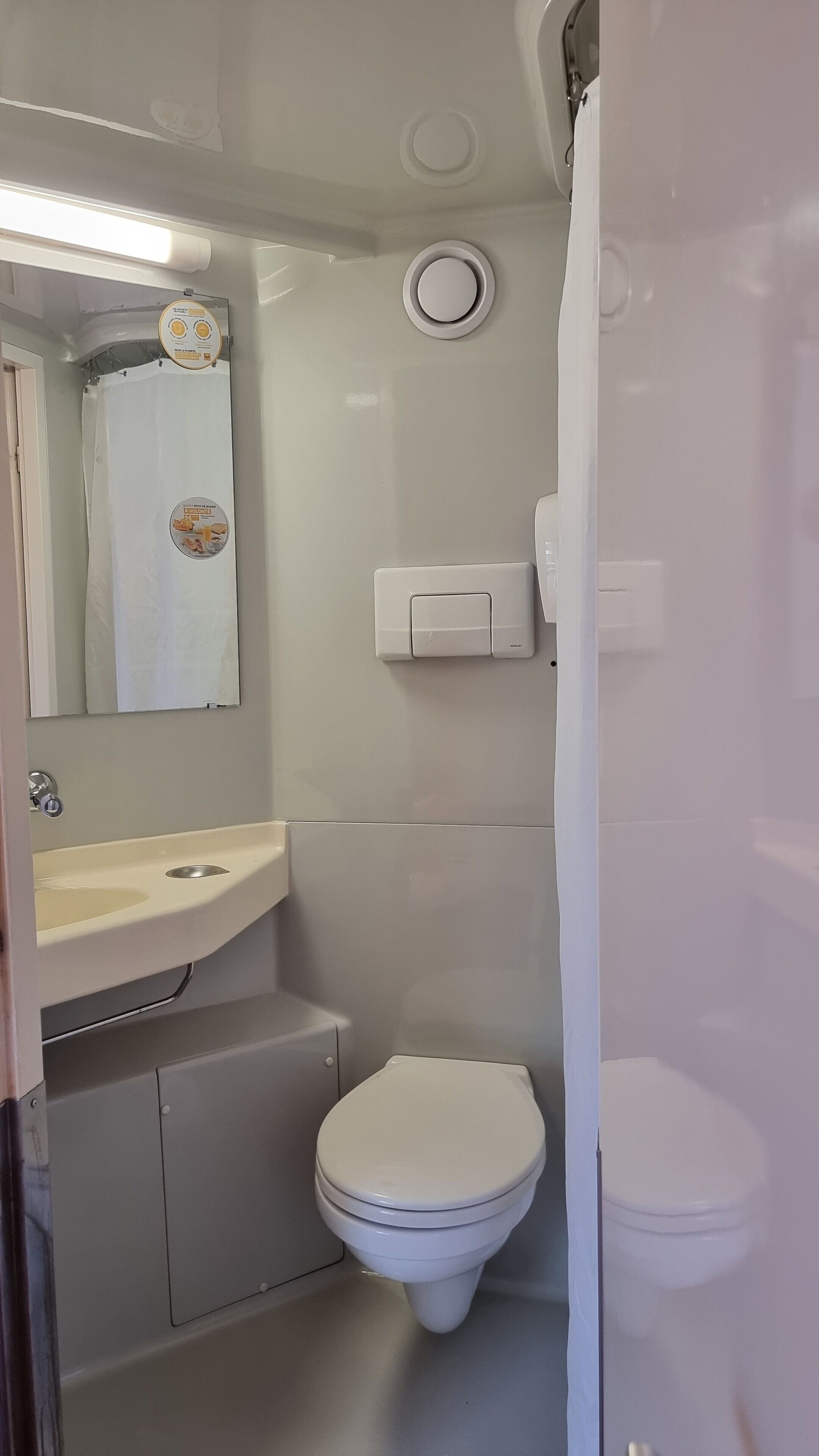 A small, clean bathroom with a toilet, sink, and mirror.