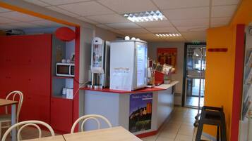 A restaurant interior with a counter, seating area, and a refrigerator.