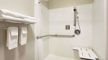 A shower with a grab bar, a towel rack with folded towels, and a shower control panel.