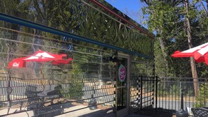 A patio area with outdoor seating, a glass enclosure, and a sign indicating the establishment is open 24 hours. - Travelodge by Wyndham Dunsmuir (Dunsmuir)