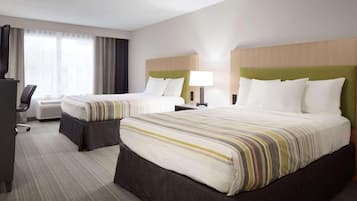 Habitación de hotel con dos camas, un escritorio y una silla.