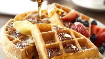 Uma pilha de waffles coberta com manteiga, xarope e frutas vermelhas frescas.