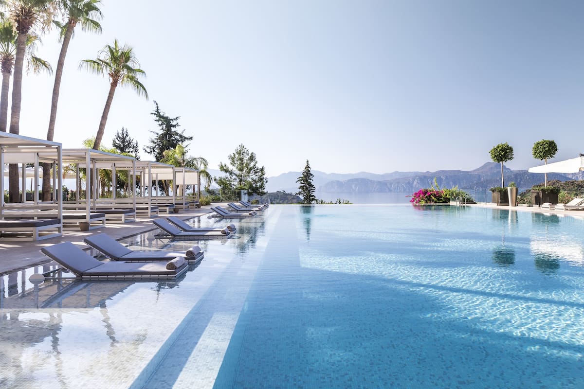 A pool area with lounge chairs and a view of mountains.