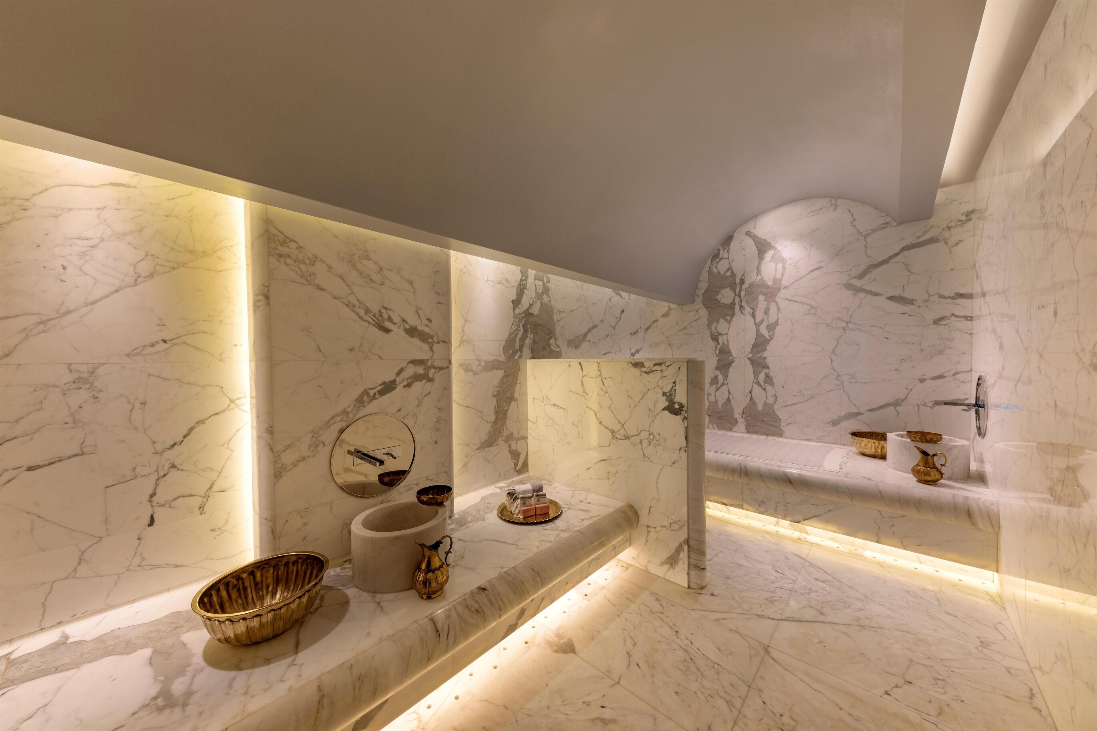 A modern bathroom with marble walls and a built-in sink.