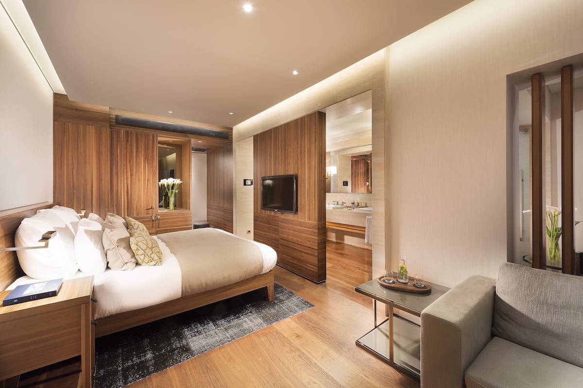 A modern hotel room with a large bed, a sofa, a small table, and a TV.