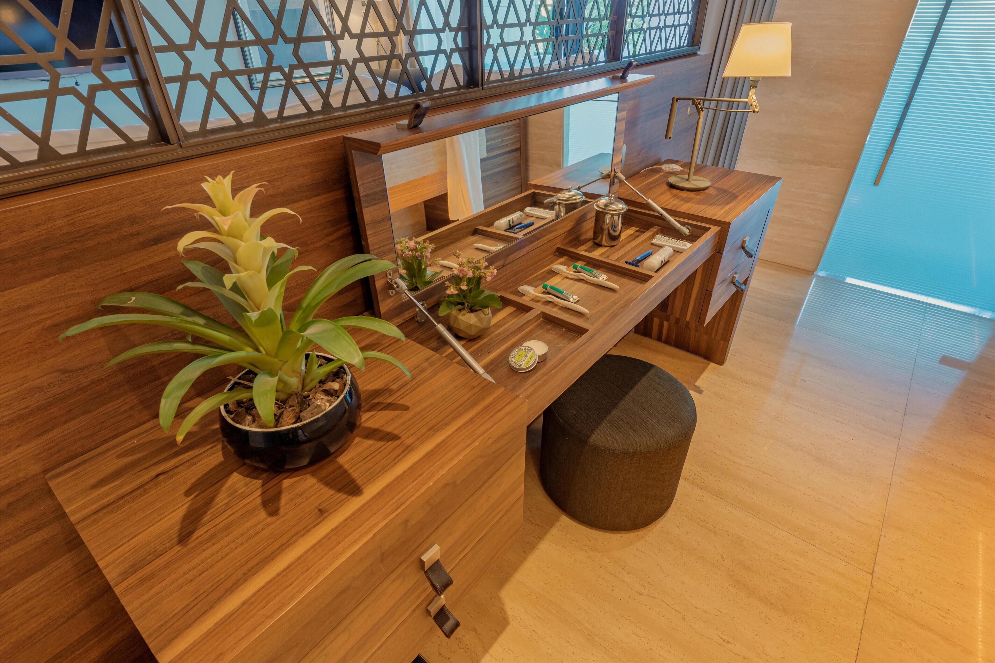 Un mostrador de recepción de madera con una planta en maceta, un espejo y una lámpara.