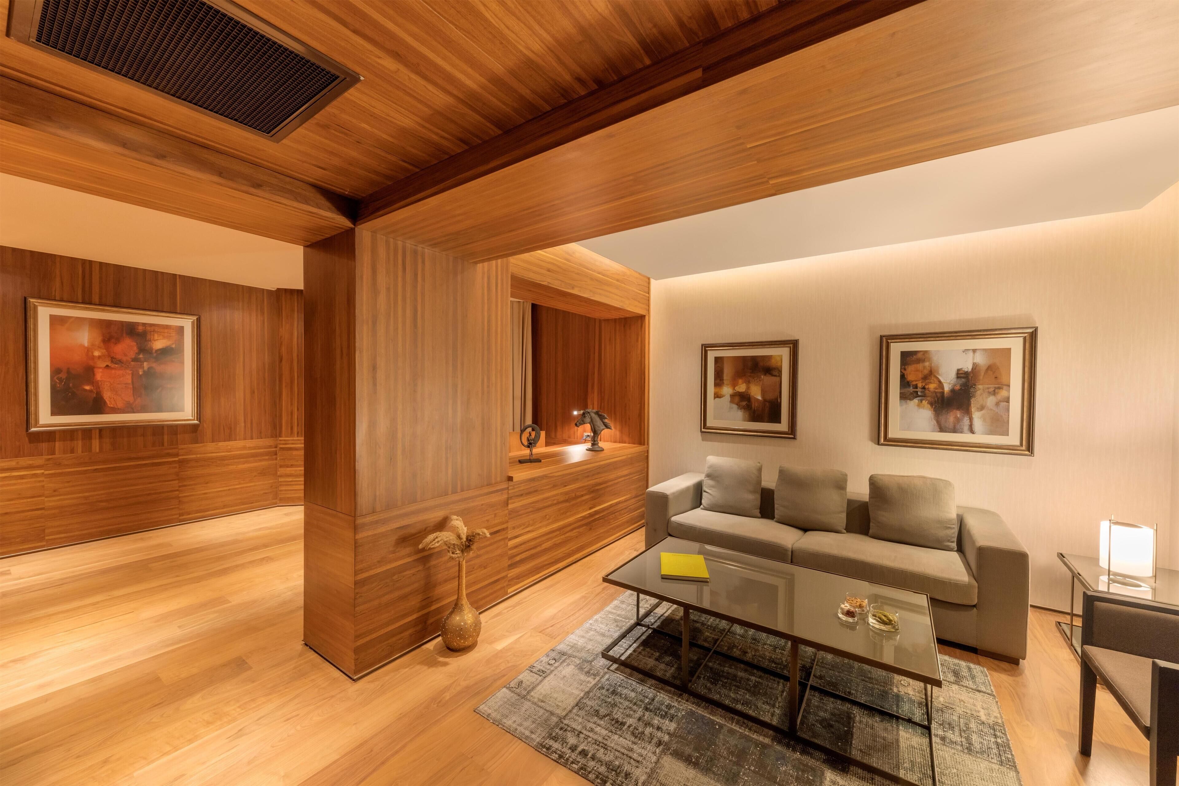 A modern living room with a wooden ceiling, a sofa, a coffee table, and framed artwork on the walls.