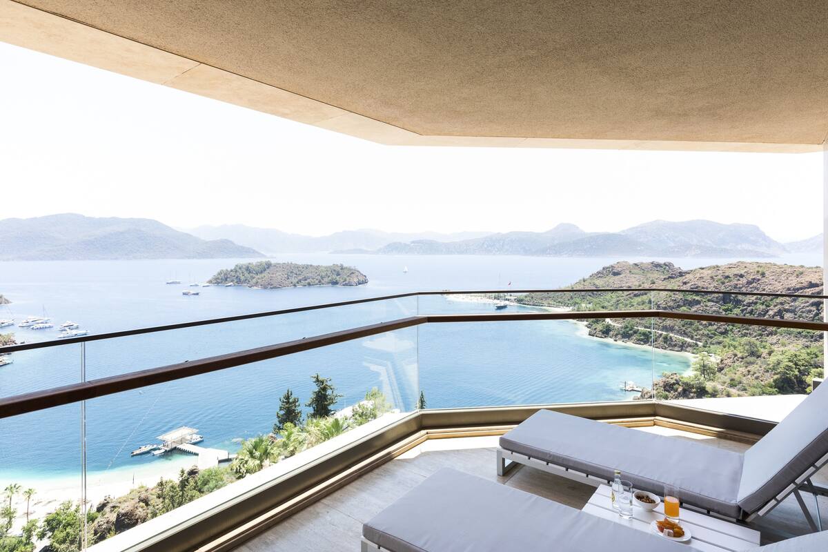 A balcony with a view of a large body of water, boats, and distant islands.