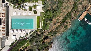 An aerial view of a resort with a large swimming pool, a rocky coastline, and a dock with boats. - D Maris Bay (Marmaris)