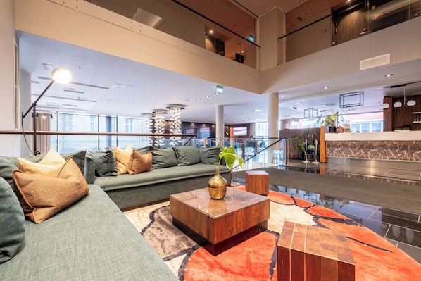 A spacious lobby with a green sofa, a wooden coffee table, and a modern chandelier.