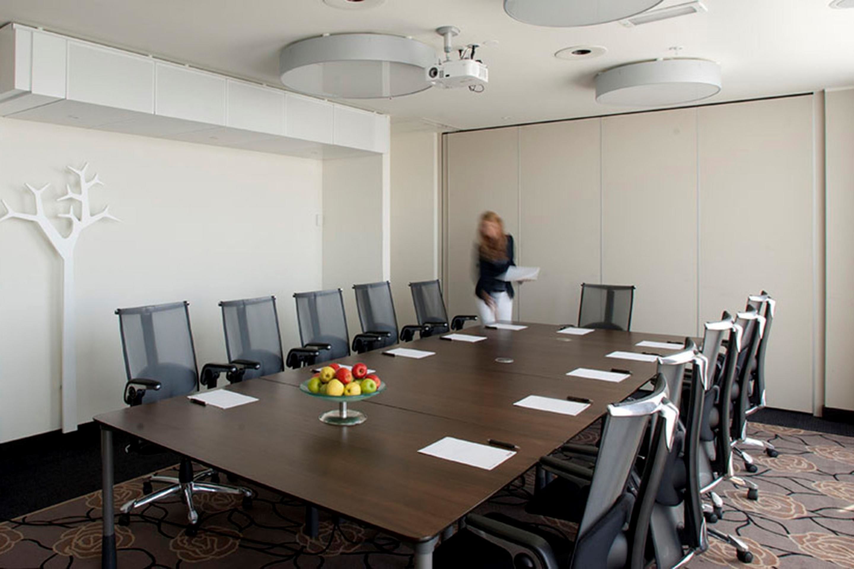 A conference room with a long table, chairs, and a fruit bowl.