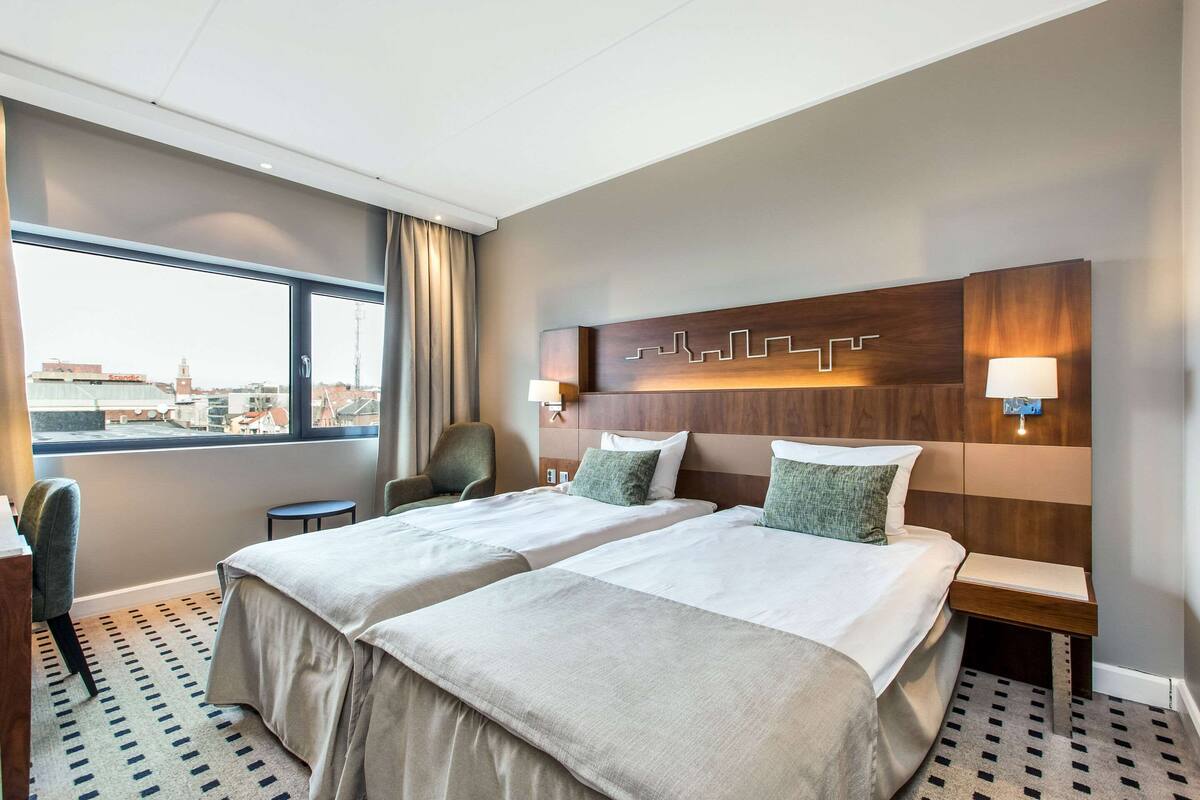 A hotel room with two beds, a view of the city, and a modern design.