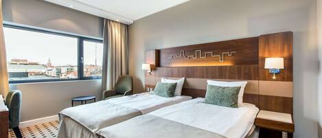 Ett hotellrum med två sängar, utsikt över staden och en modern design.