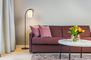 Una sala de estar moderna con un sofá, una lámpara de pie y una mesa de centro con un jarrón de flores.