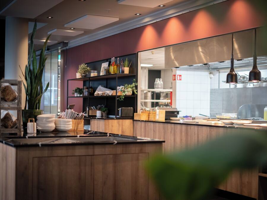 Een moderne keuken met houten kastjes, een groot eiland en diverse keukenapparaten.