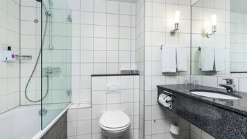 A modern bathroom with a glass-enclosed shower, a white toilet, and a granite countertop sink.
