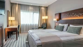 A hotel room with a large bed, two bedside tables, a desk, and a chair.