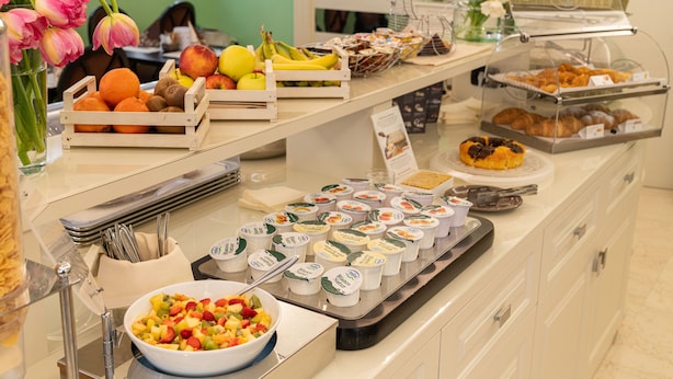 A buffet with various food items including fruits, pastries, and yogurt containers. - Hotel Roxy Plaza (Soave)