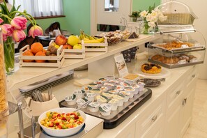 Un buffet proposant une variété d’aliments, notamment des fruits, des pâtisseries et des yaourts.