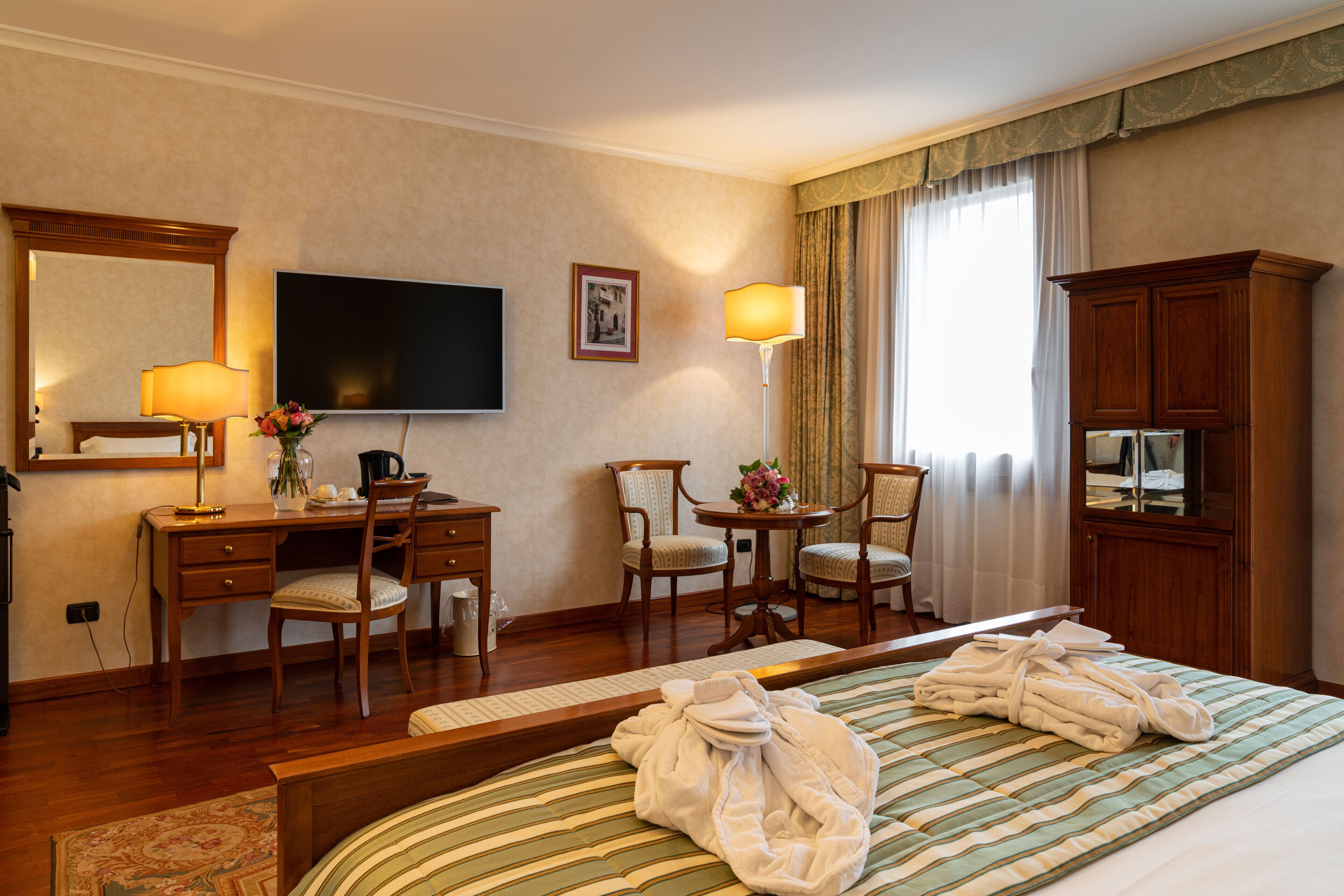A hotel room with a bed, a desk, a chair, a television, and a cabinet.