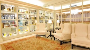 A well-lit room with a large, ornate rug, white armchairs, and a glass display case filled with various items. - Hotel Roxy Plaza (Soave)