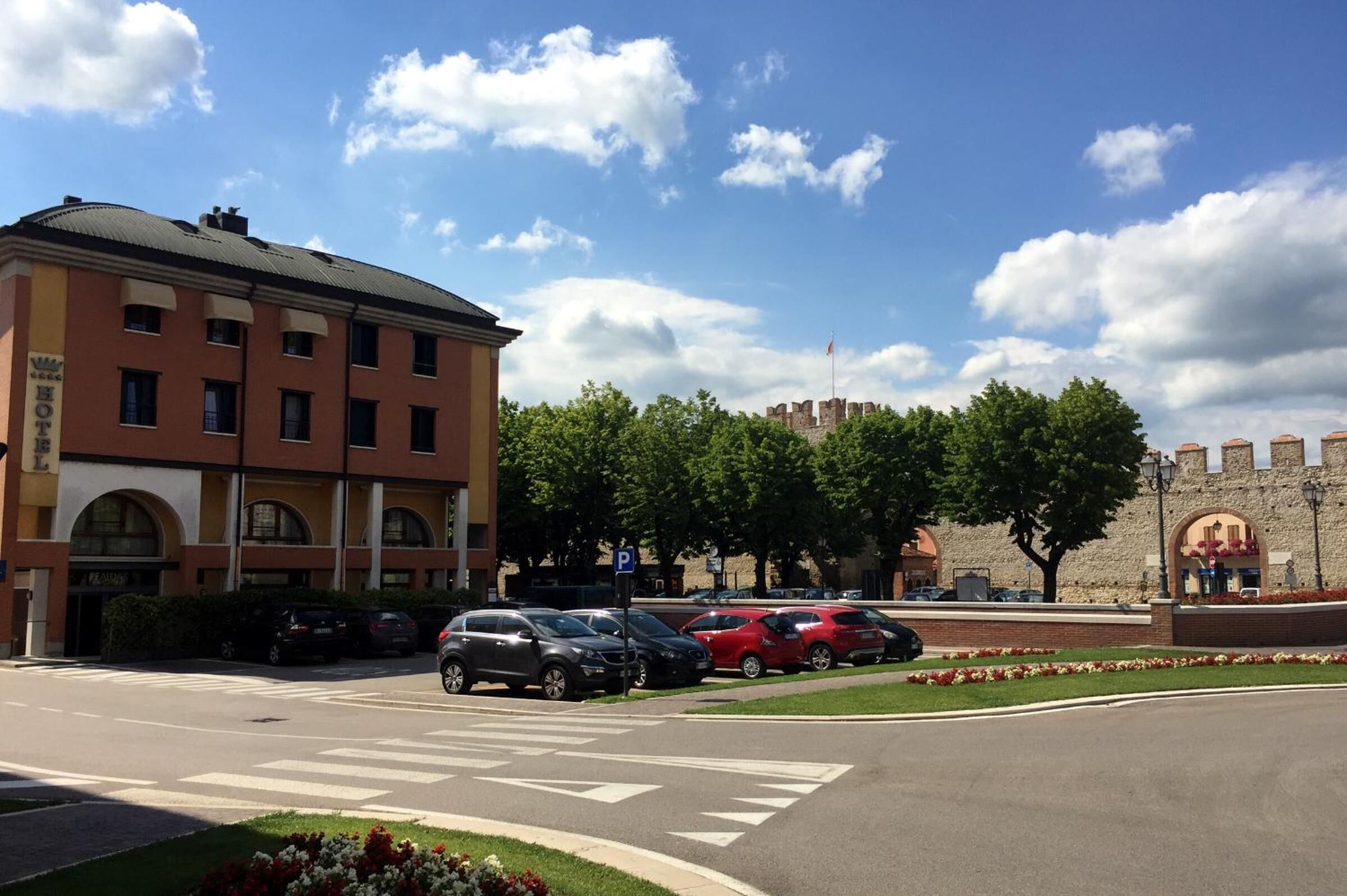 Un hotel con aparcamiento, una estructura que recuerda a un castillo al fondo, y cielo despejado.