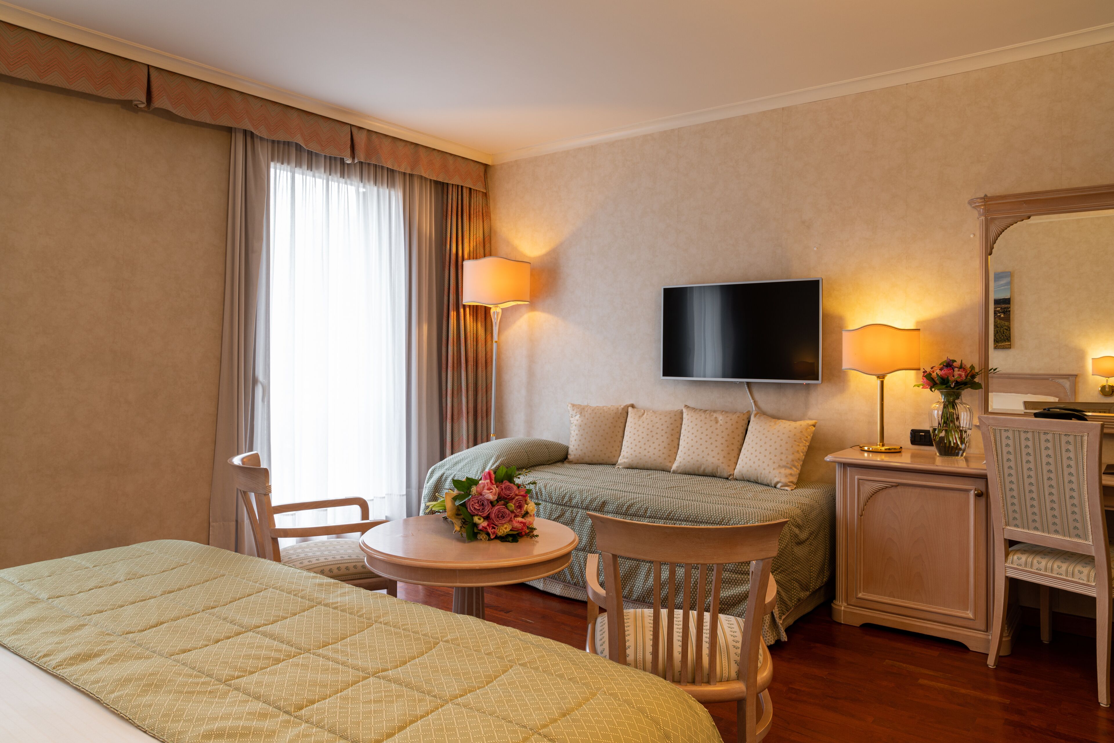 Una habitación de hotel con cama, escritorio, silla, televisor y sofá.