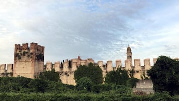 A historic stone castle with multiple towers and a central keep, surrounded by dense greenery.