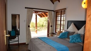 A bedroom with a bed, a desk, and a window with curtains.