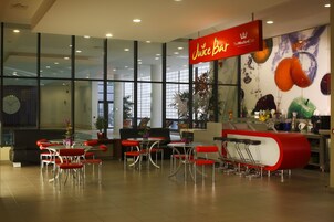 A Juice Bar with a modern interior, including red and white bar stools, a large window, and a wall mural of fruits.